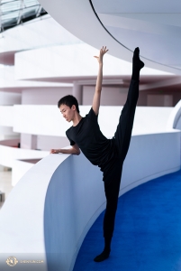 Dancer Zhiheng Li peeks at the lower level as he warms up. (Photo by Kenji Kobayashi)
