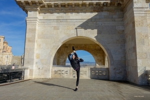 Dans le cadre pittoresque du bastion Saint-Rémy de Cagliari, en Italie, une danseuse prend une pose gracieuse. Ce monument emblématique, construit à la fin du XIXe siècle, offre une vue panoramique de la ville italienne.
